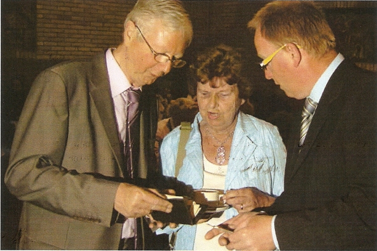 Doki, pastor Nico Essen en Gert van Dompseler bekijken de portefeuille. Tijdens een bijzondere herdenking in de Hofkerk werd de portefeuille van Jan van Beers aan de familie overhandigd. 