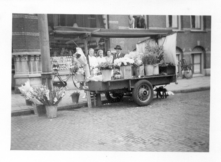 Bloemenstal Zomer 1948: opa Meijer met zijn bloemenstal. Bij hem staan beide dochters en de schoondochter van de filiaalchef de Lang. Hij en zijn echtgenote overzien, boven uit het raam hangend, de hele scene. (Met dank aan mevrouw Groot) 