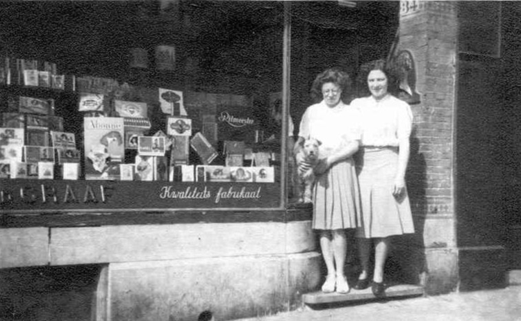 Mevrouw Angeline van de Graaf (links) voor de sigarenwinkel van haar ouders, Middenweg 34 in 1943.  