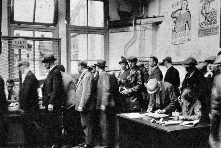 Stempellokaal. Economie, Nederland. Crisis jaren '30: een rij werklozen in een stempellokaal. [Amsterdam-Noord], omstreeks 1933.<br />Bron: Wikipedia Commons. 